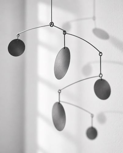 Detail eines Mobiles: Feine Drähte halten mehrere Metallscheiben im Gleichgewicht, ein Sinnbild für Beziehungen in der systemischen Therapie